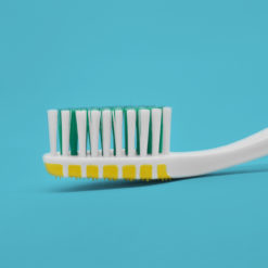 Cepillo dental para adultos detalle de la cabeza del cepillo cerdas bicolor y limpiador de lengua